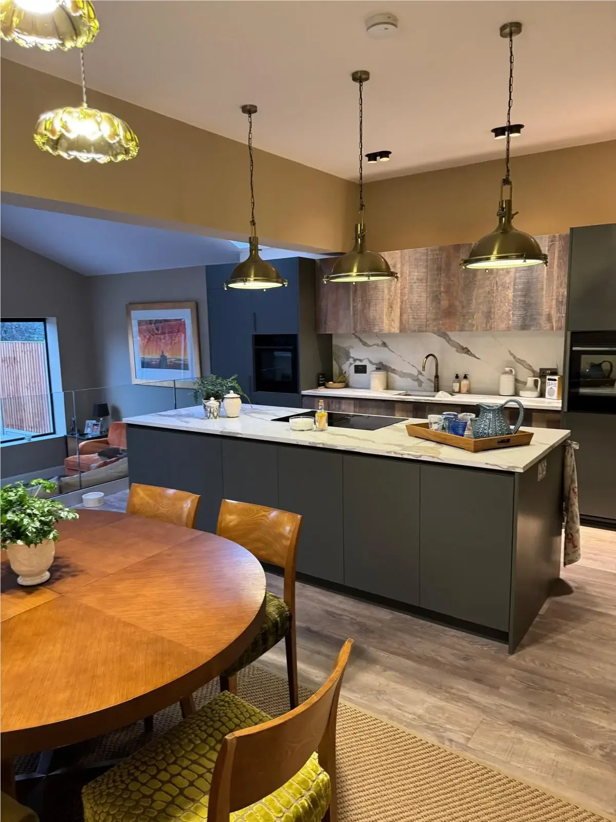 Completed dark kitchen with a marble-effect island and brass pendant lights